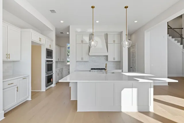 a large white kitchen with stainless steel appliances