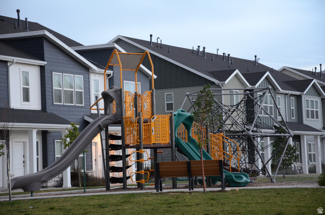 1842 South 1280th Street West Logan, UT 84321 - Photo 20 of 21 Community playground featuring a slide, climbing structure, and bench seating, set against a backdrop of modern townhomes with dark roofing and varied siding