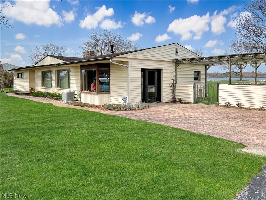 4663 East Harbor Road Port Clinton, OH 43452 - Photo 2 of 31 Ranch-style house with a patio, a front yard, central AC unit, and a pergola