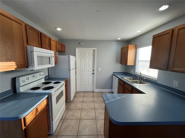 a kitchen with stainless steel appliances a stove a sink a microwave a refrigerator and white cabinets