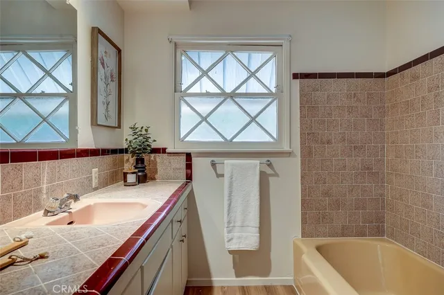 a bathroom with a granite countertop sink a bathtub window and mirror