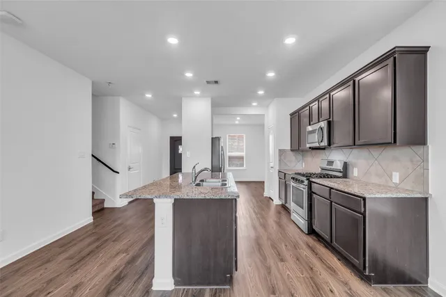 a large kitchen with stainless steel appliances lots of counter space and wooden floor