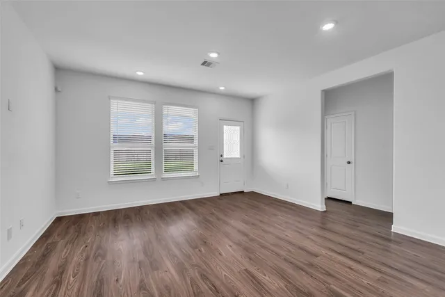a view of an empty room with wooden floor and a window