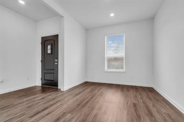 a view of an empty room with wooden floor and a window