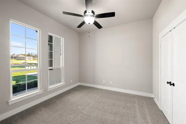 en empty room with windows and ceiling fan