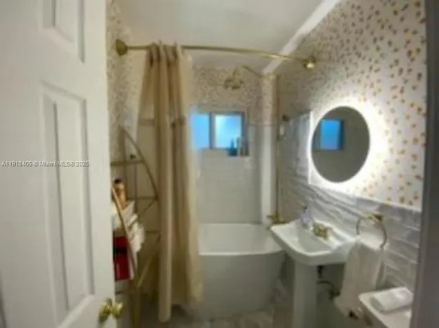 a bathroom with a sink and mirror with bathtub
