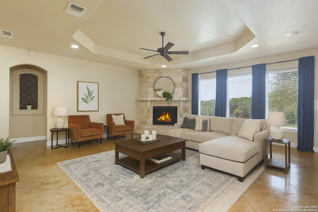 a view of a livingroom with a fireplace a ceiling fan and windows