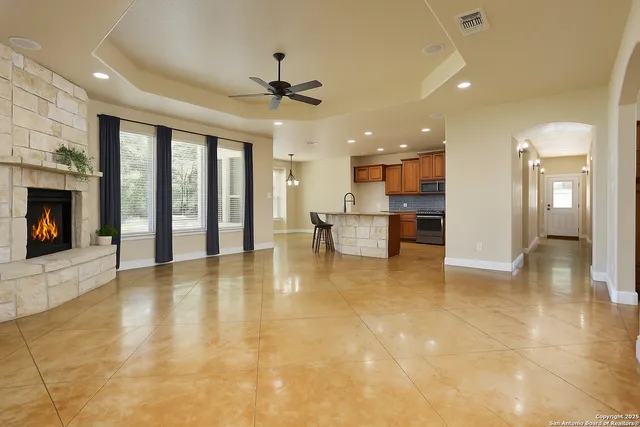 a view of an empty room with a fireplace and a ceiling fan