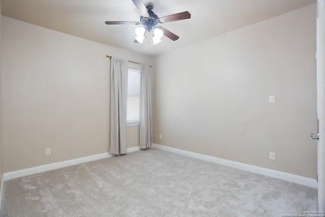 an empty room with a chandelier fan and closet area