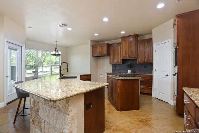 a kitchen with stainless steel appliances granite countertop a refrigerator a sink a stove a microwave and wooden cabinets