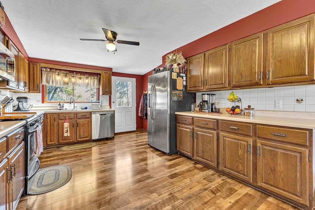 6437 Tuscarawas Road Midland, PA 15059 - Photo 12 of 29 a kitchen with stainless steel appliances granite countertop a refrigerator a sink dishwasher a stove with wooden cabinets and floor