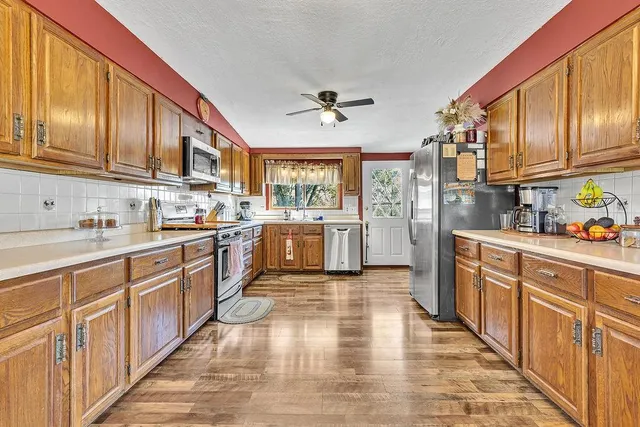 a kitchen with stainless steel appliances granite countertop lots of counter top space and wooden floors