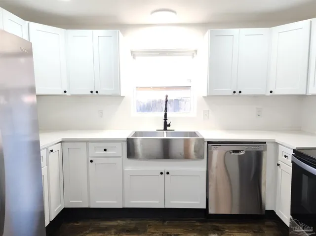 a kitchen with white cabinets and sink