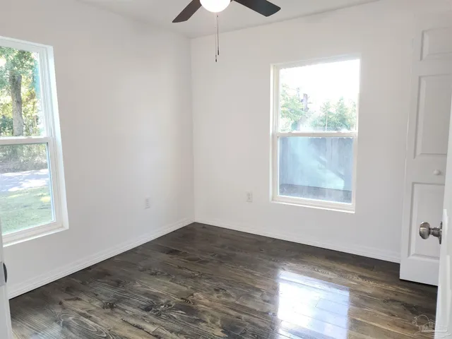 a view of an empty room with wooden floor and a window