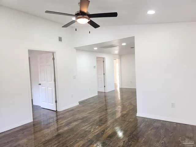 an empty room with wooden floor and ceiling fan
