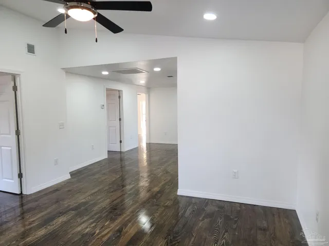 an empty room with wooden floor chandelier fan and closet area