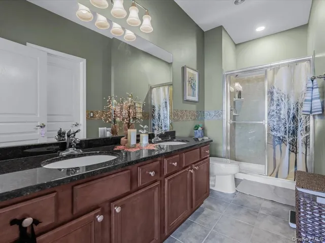 a bathroom with a granite countertop sink a toilet a mirror and shower