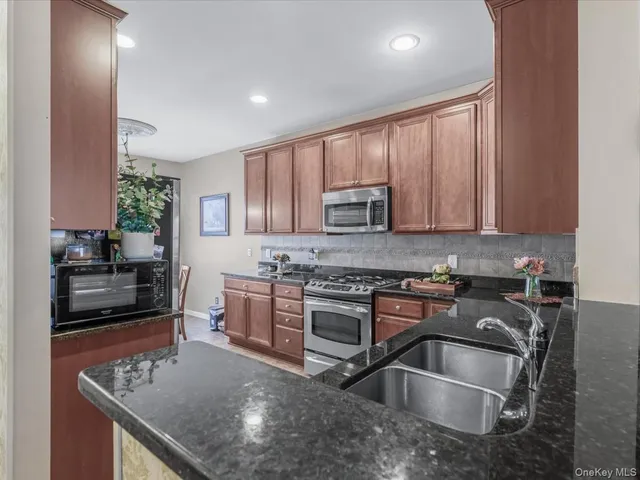 a kitchen with kitchen island granite countertop a sink stove and cabinets