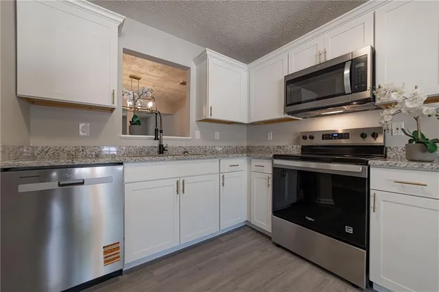 a kitchen with granite countertop a stove and a microwave