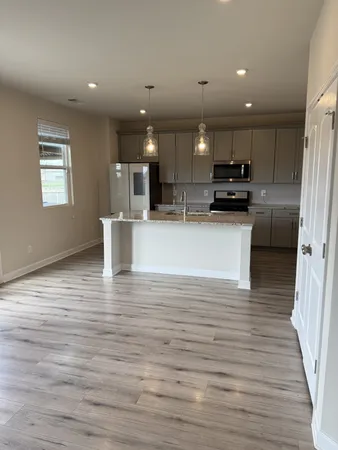 a view of an empty room with wooden floor and windows