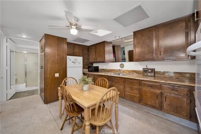 a kitchen with stainless steel appliances granite countertop a sink a stove a refrigerator cabinets and chairs