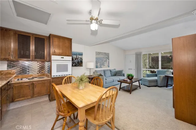 a living room with stainless steel appliances furniture a fireplace and a open kitchen view
