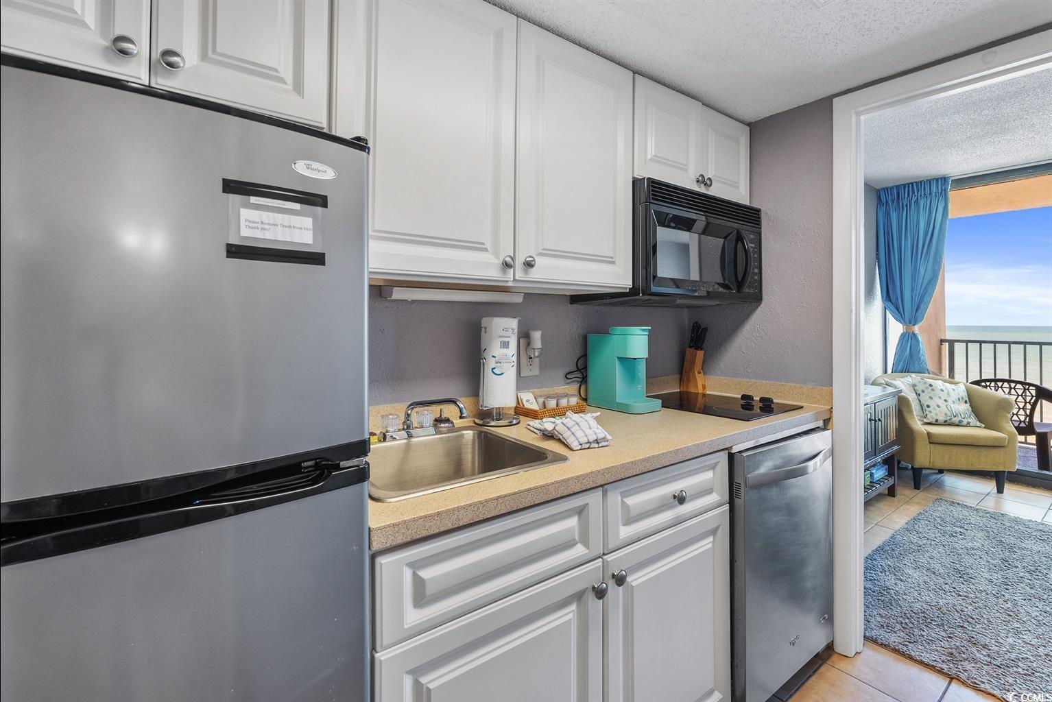 201 74th Avenue North, Unit 2527 Myrtle Beach, SC 29572 - Photo 6 of 18 Kitchen featuring black appliances, light countertops, white cabinets, light tile patterned floors, and a textured ceiling