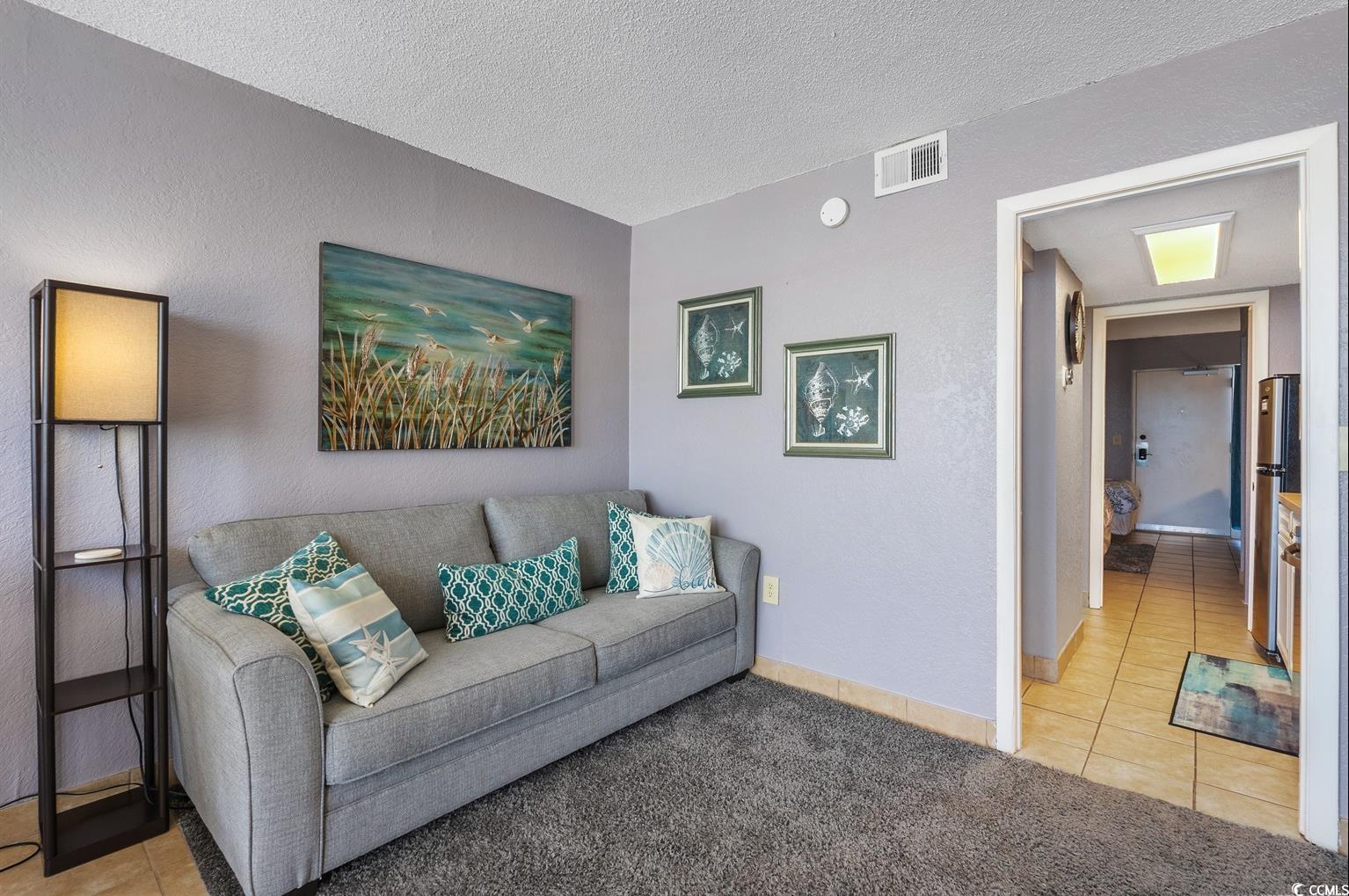 201 74th Avenue North, Unit 2527 Myrtle Beach, SC 29572 - Photo 9 of 18 Living area with light tile patterned floors, a textured ceiling, light colored carpet, and a textured wall