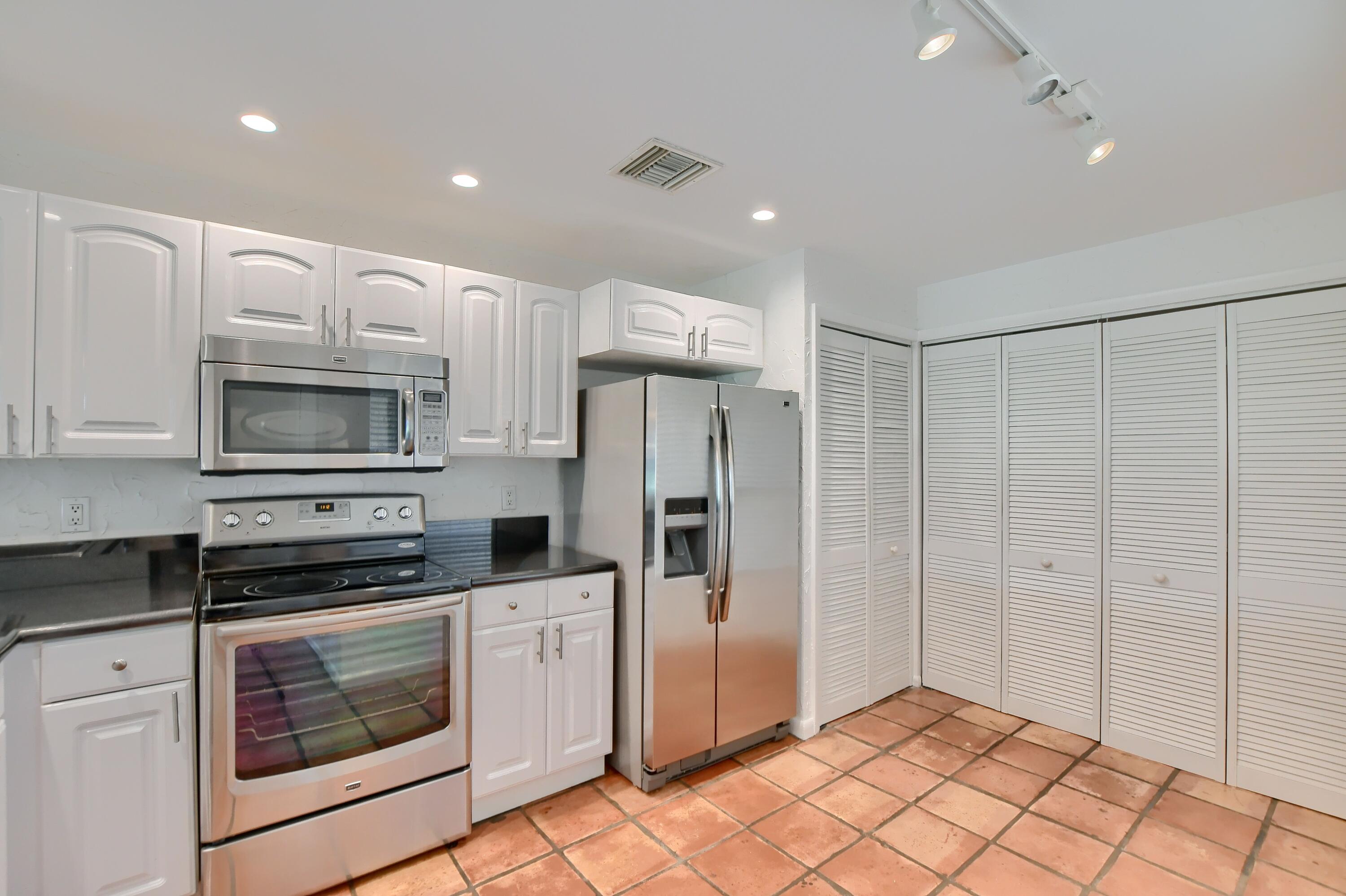 7495 La Paz Boulevard, Unit 105 Boca Raton, FL 33433 - Photo 11 of 29 a kitchen with stainless steel appliances granite countertop a refrigerator and a stove top oven