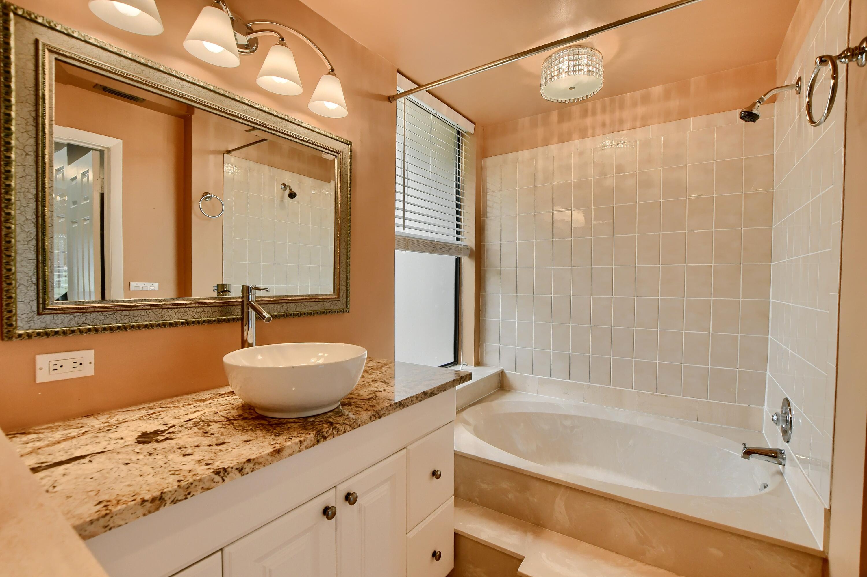 7495 La Paz Boulevard, Unit 105 Boca Raton, FL 33433 - Photo 23 of 29 a bathroom with a granite countertop sink a toilet and bathtub