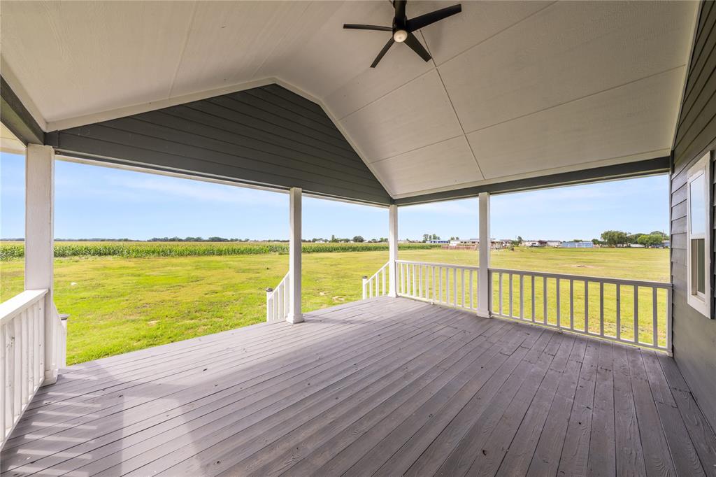 1128 Newton Road Ferris, TX 75125 - Photo 25 of 28 Expansive covered porch featuring a painted wood-finish deck, white railing, and a vaulted ceiling with a ceiling fan