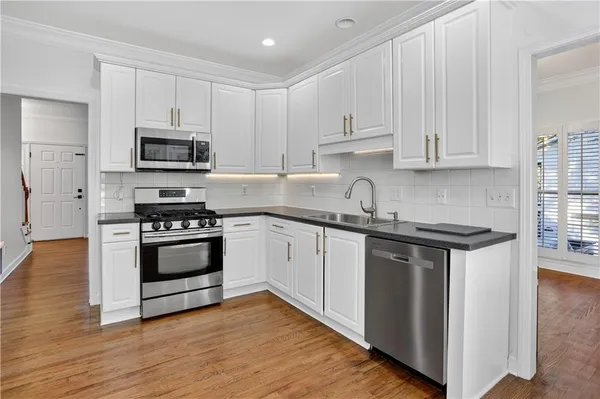 a kitchen with stainless steel appliances granite countertop a refrigerator a stove and a wooden floors