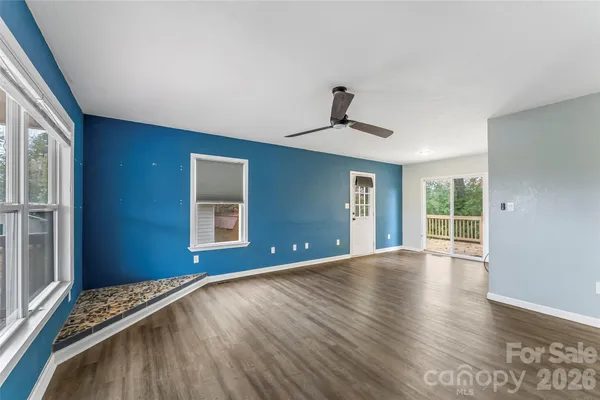 a view of an empty room with a window and wooden floor