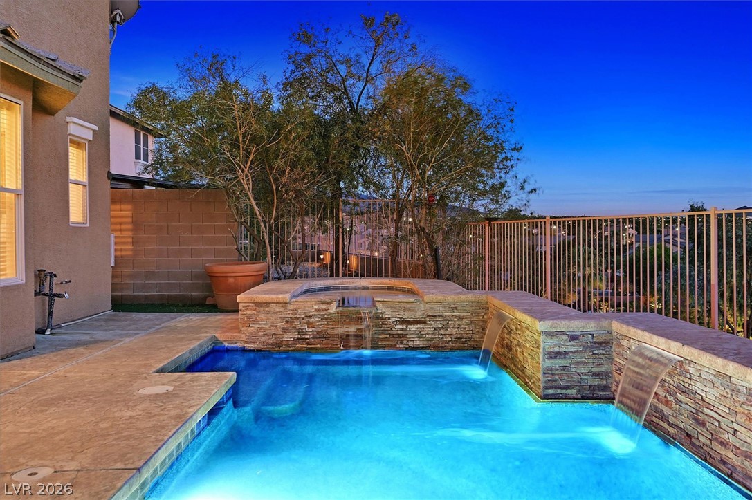 2447 Kaymin Ridge Road Henderson, NV 89052 - Photo 34 of 40 An inviting backyard oasis showcases a stone-accented swimming pool with multiple cascading waterfalls.