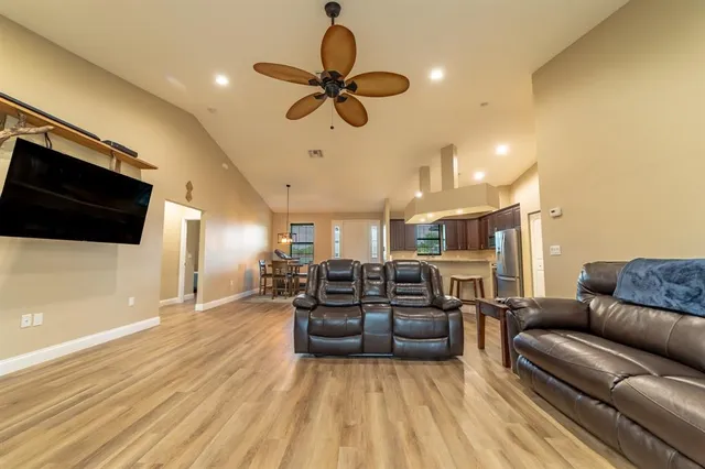 a living room with furniture a flat screen tv and kitchen view