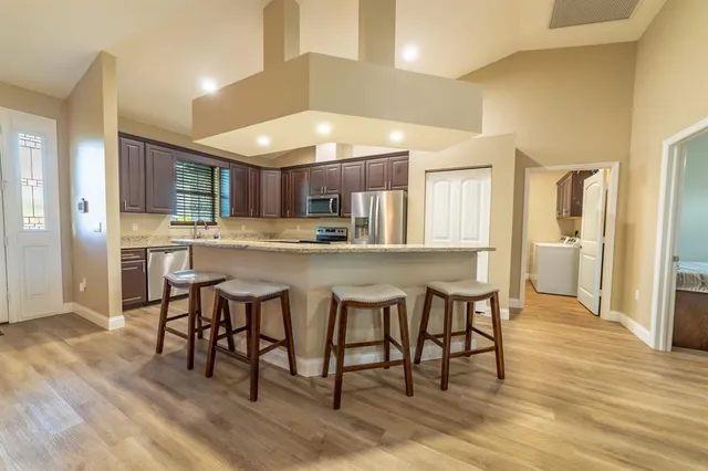 a kitchen with stainless steel appliances granite countertop a table chairs and a refrigerator