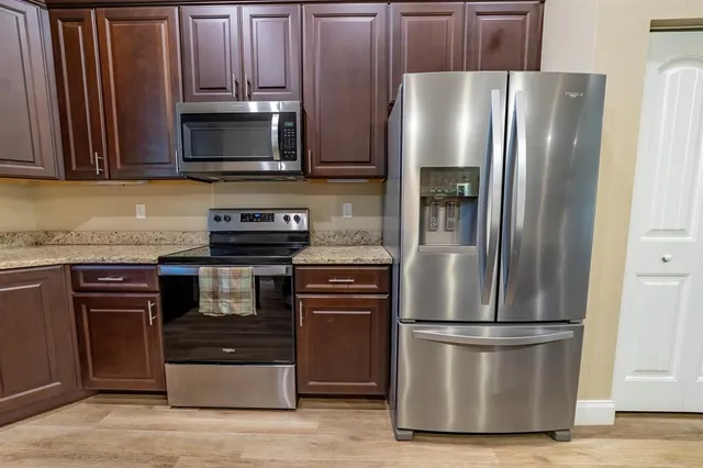 a kitchen with stainless steel appliances granite countertop a refrigerator and a stove top oven