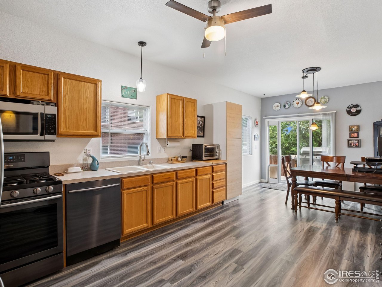 6735 West 37th Place Wheat Ridge, CO 80033 - Photo 3 of 17 a kitchen with stainless steel appliances granite countertop a stove a sink dishwasher a dining table and chairs with wooden floor