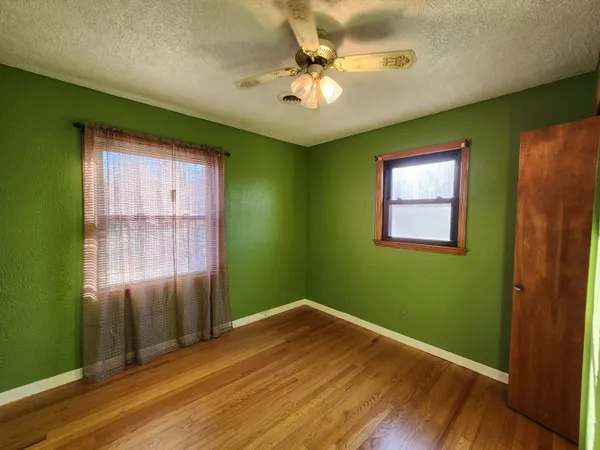 a view of an empty room with window and wooden floor