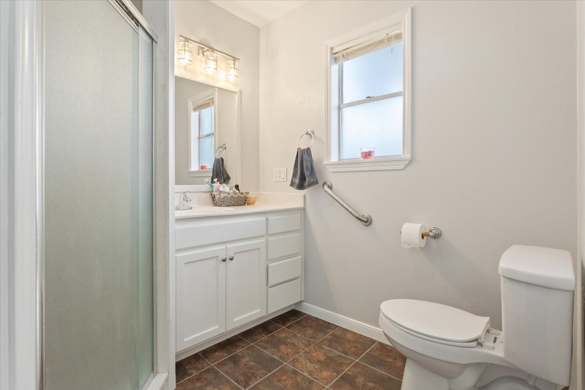 1607 North Harding Avenue Cameron, TX 76520 - Photo 20 of 37 A pristine bathroom featuring a glass-enclosed shower and practical grab bars.