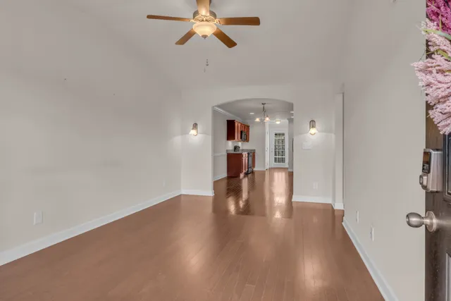 a view of an empty room with wooden floor and a ceiling fan