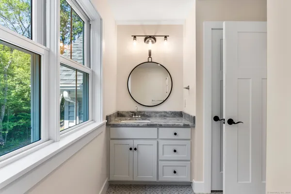 a bathroom with a granite countertop toilet a sink and a mirror