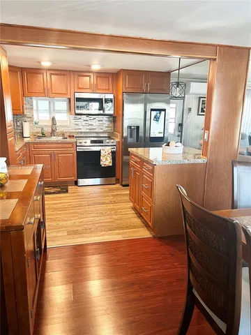 a kitchen with stainless steel appliances wooden floor a table and chairs