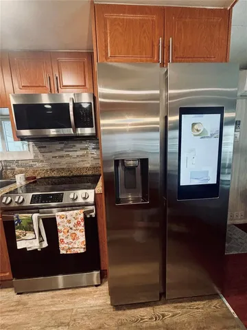 a view of a refrigerator in kitchen and an empty room
