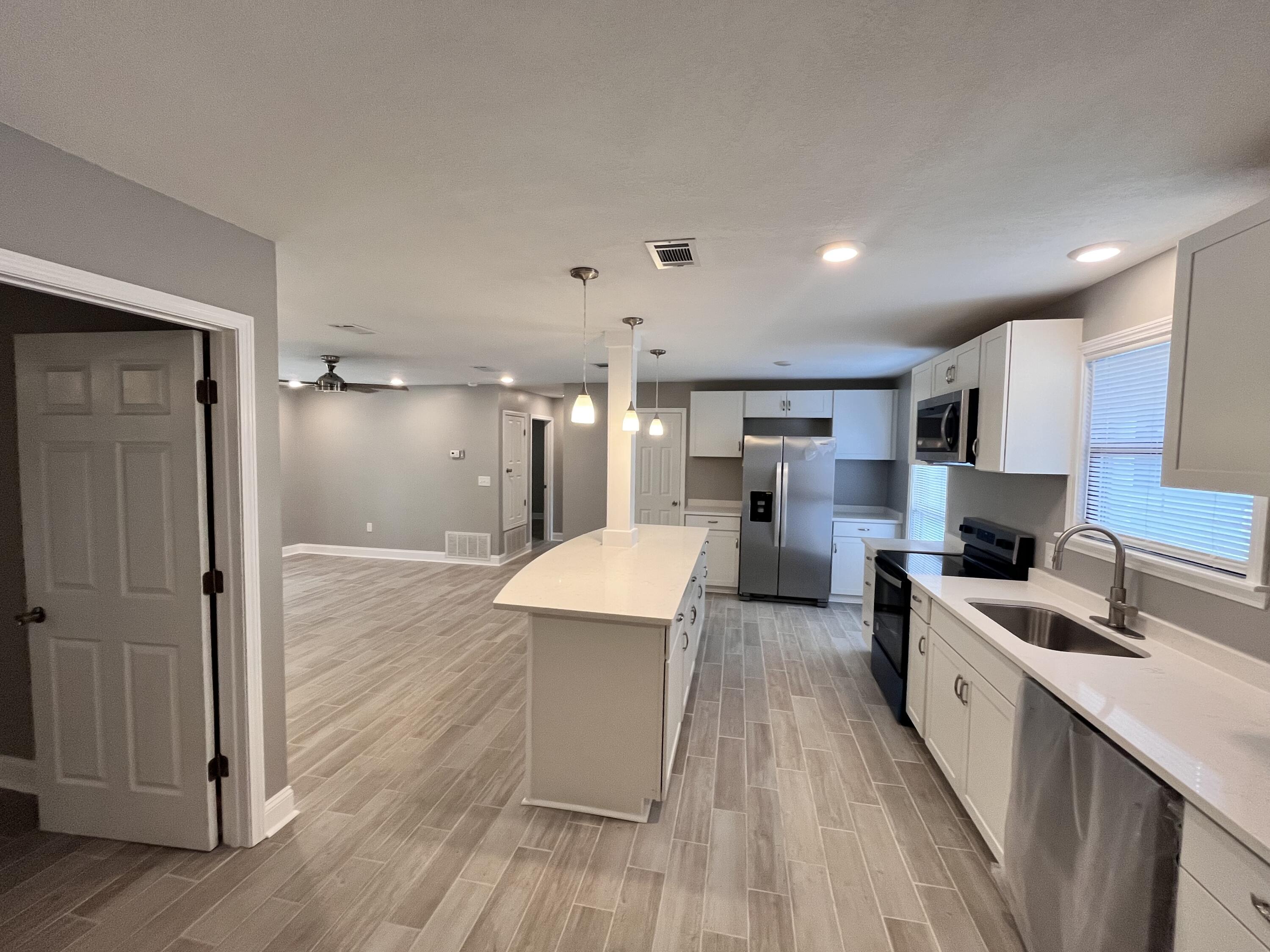 795 Bay Street Crestview, FL 32536 - Photo 3 of 16 a large kitchen with a wooden floor and stainless steel appliances