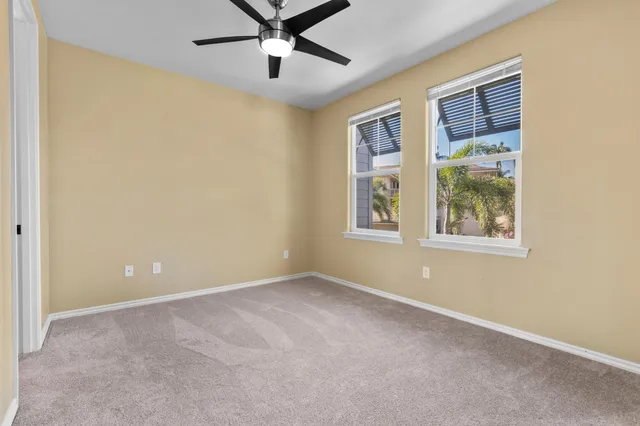 an empty room with windows and chandelier fan