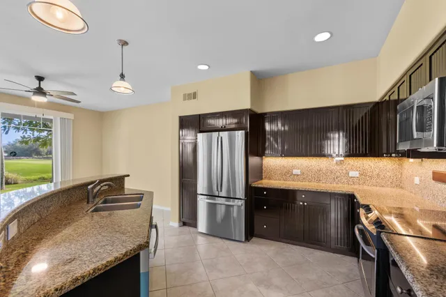 a kitchen with stainless steel appliances granite countertop a sink refrigerator and cabinets