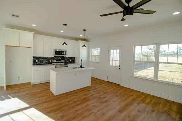 a kitchen with stainless steel appliances a refrigerator sink and white cabinets