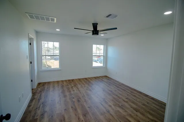 a view of empty room with wooden floor and fan