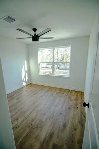 a view of empty room with wooden floor and fan